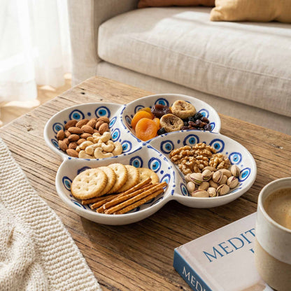 Three-section bowl with snacks on a wooden table next to a book and cup of coffee.