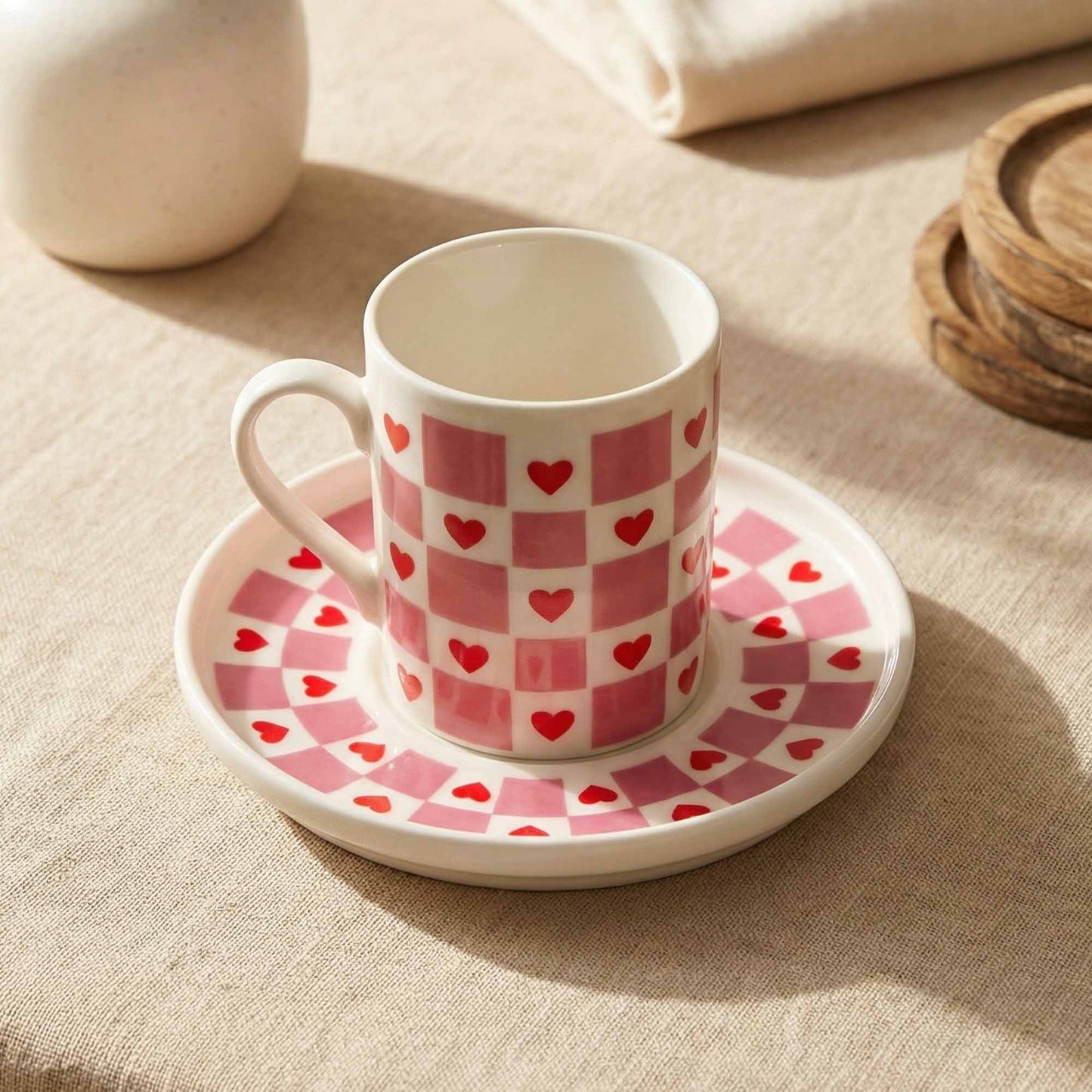 Porcelain cup and saucer with heart pattern on a beige surface