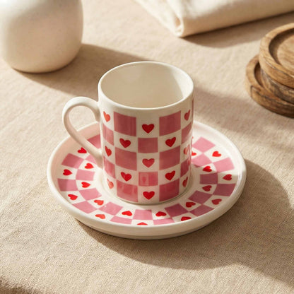Porcelain cup and saucer with heart pattern on a beige surface