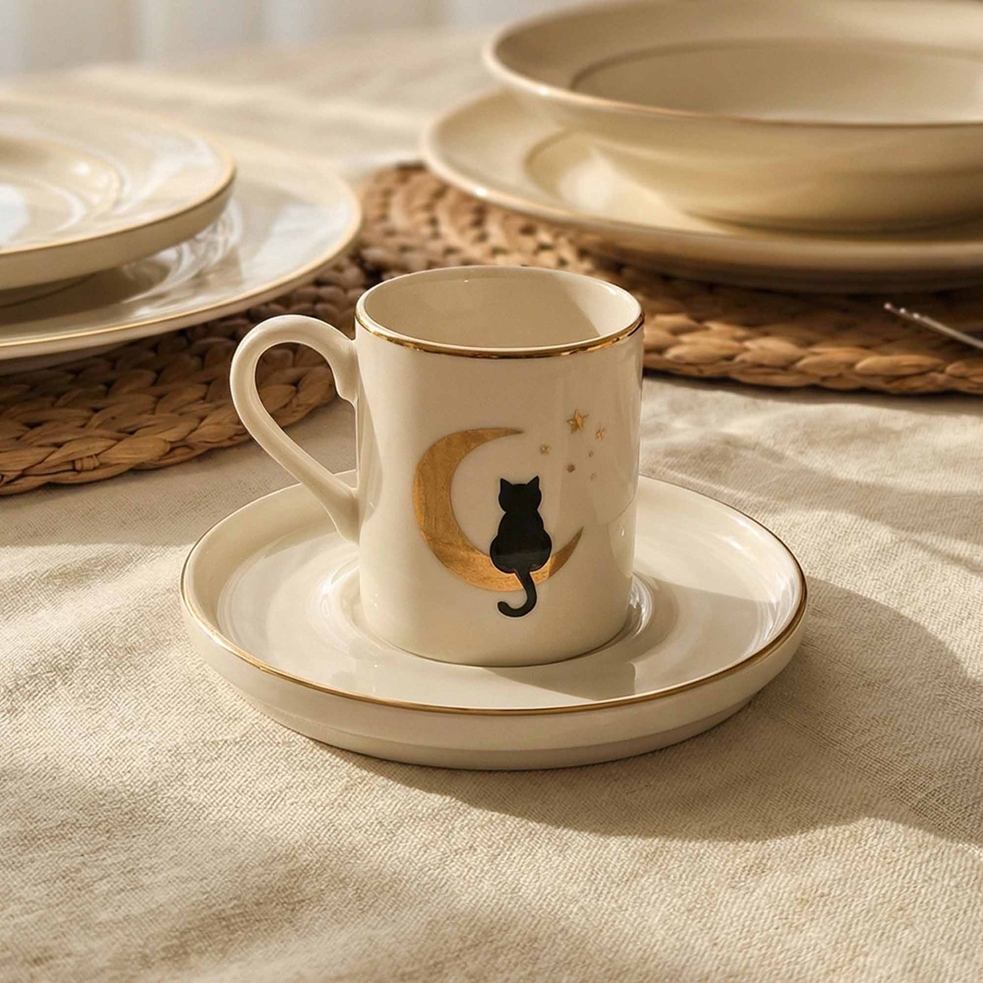 Porcelain cup with black cat design on a saucer, placed on a textured surface.