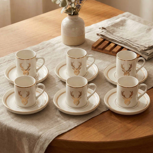 Set of porcelain cups and saucers with deer design on a wooden table.