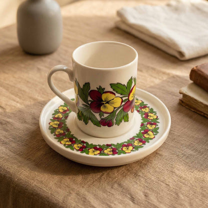 Porcelain mug and saucer with floral design on a wooden table