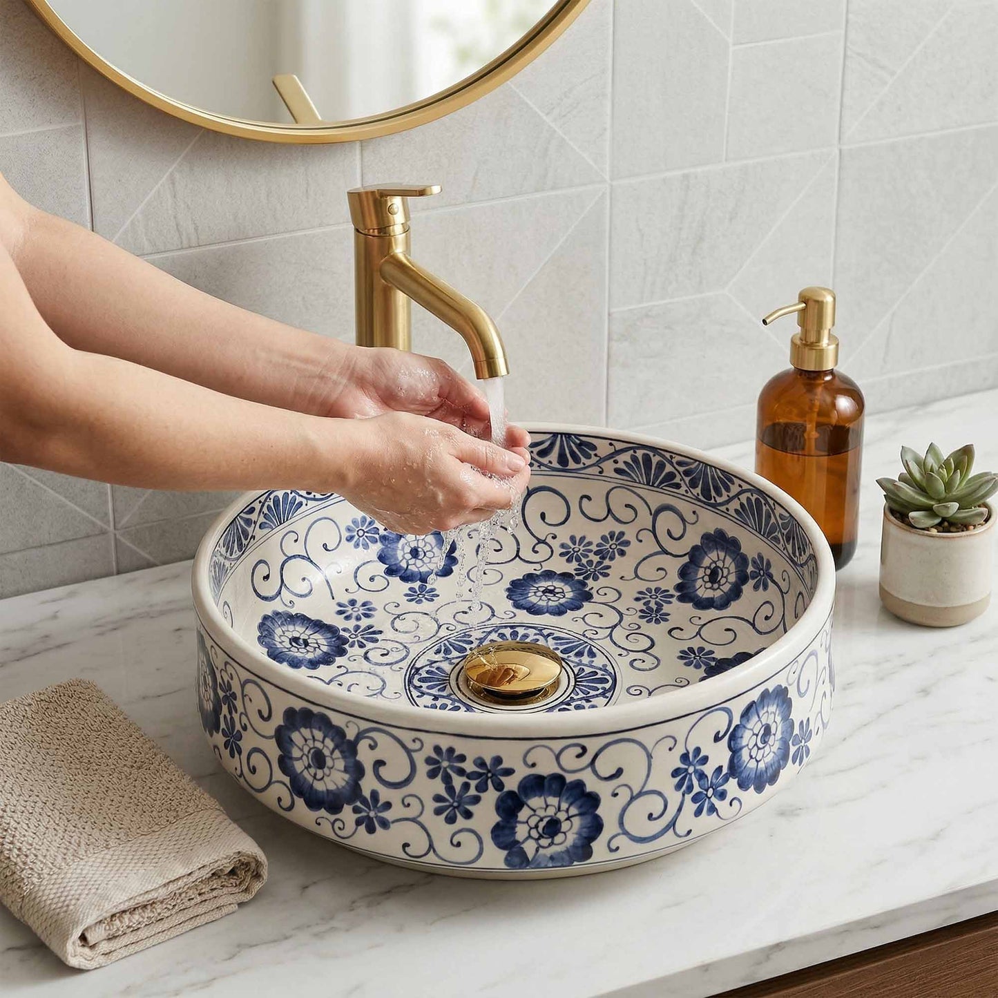 Person washing hands under a gold faucet in a bathroom with a decorative blue and white sink.