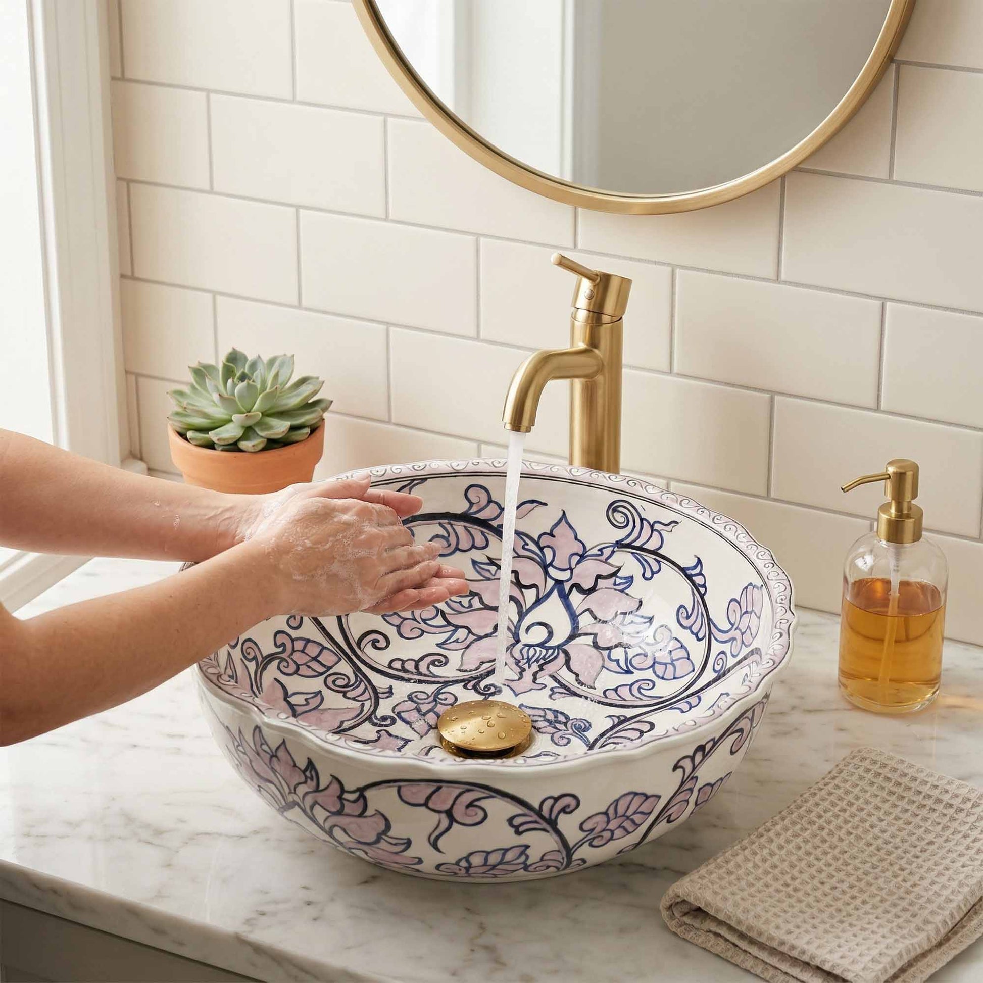 Person washing hands under a decorative sink with a gold faucet in a bathroom setting.