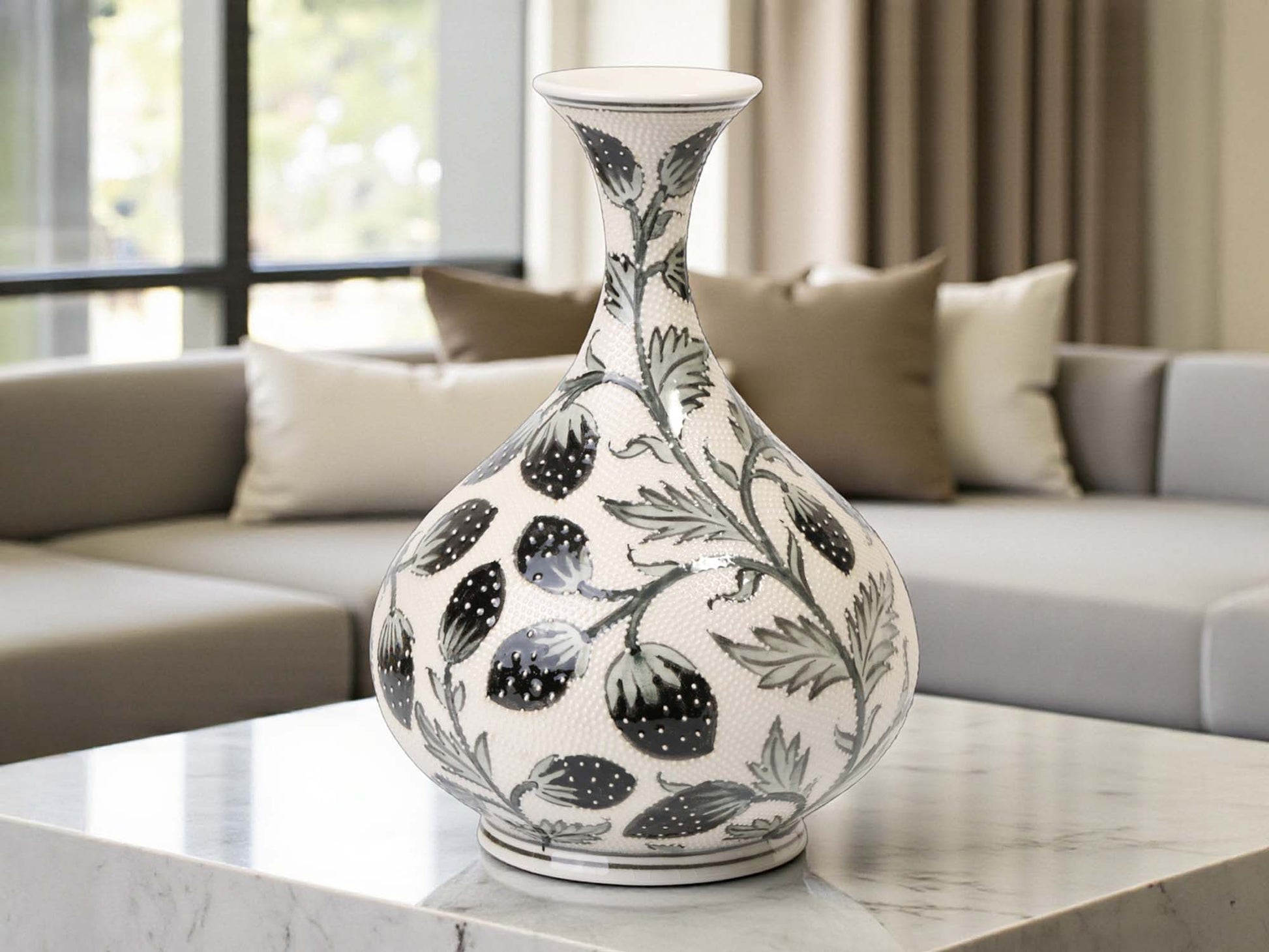 Decorative vase with black floral patterns on a marble surface in a living room setting.
