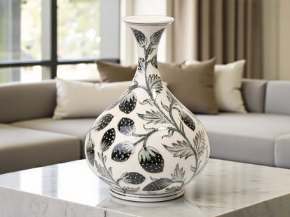 Decorative vase with black floral patterns on a marble surface in a living room setting.