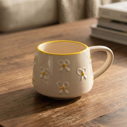 Ceramic mug with floral designs on a wooden surface