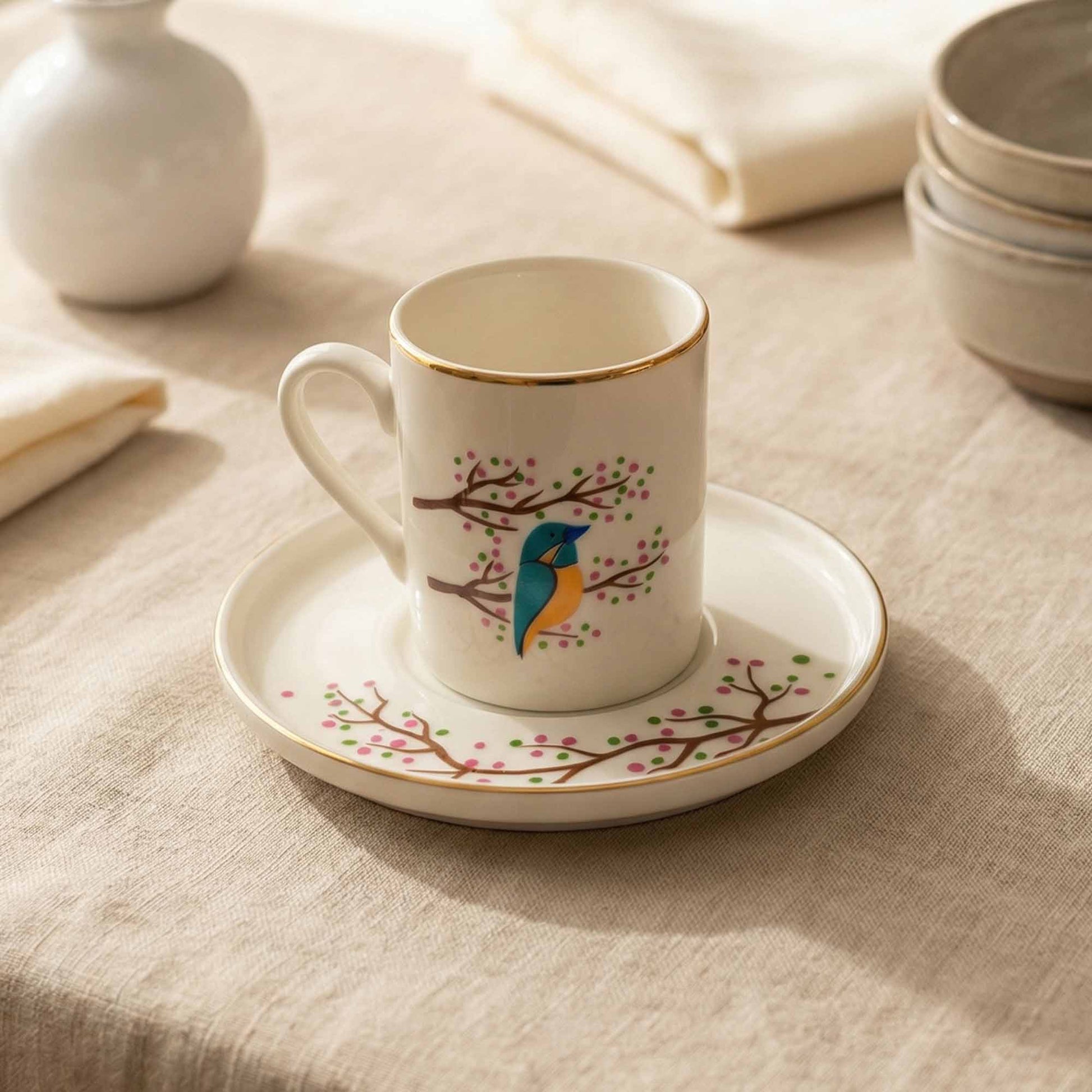 Porcelain cup and saucer with a bird design on a beige tablecloth.