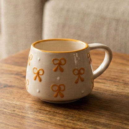 White mug with yellow bow designs on a wooden surface