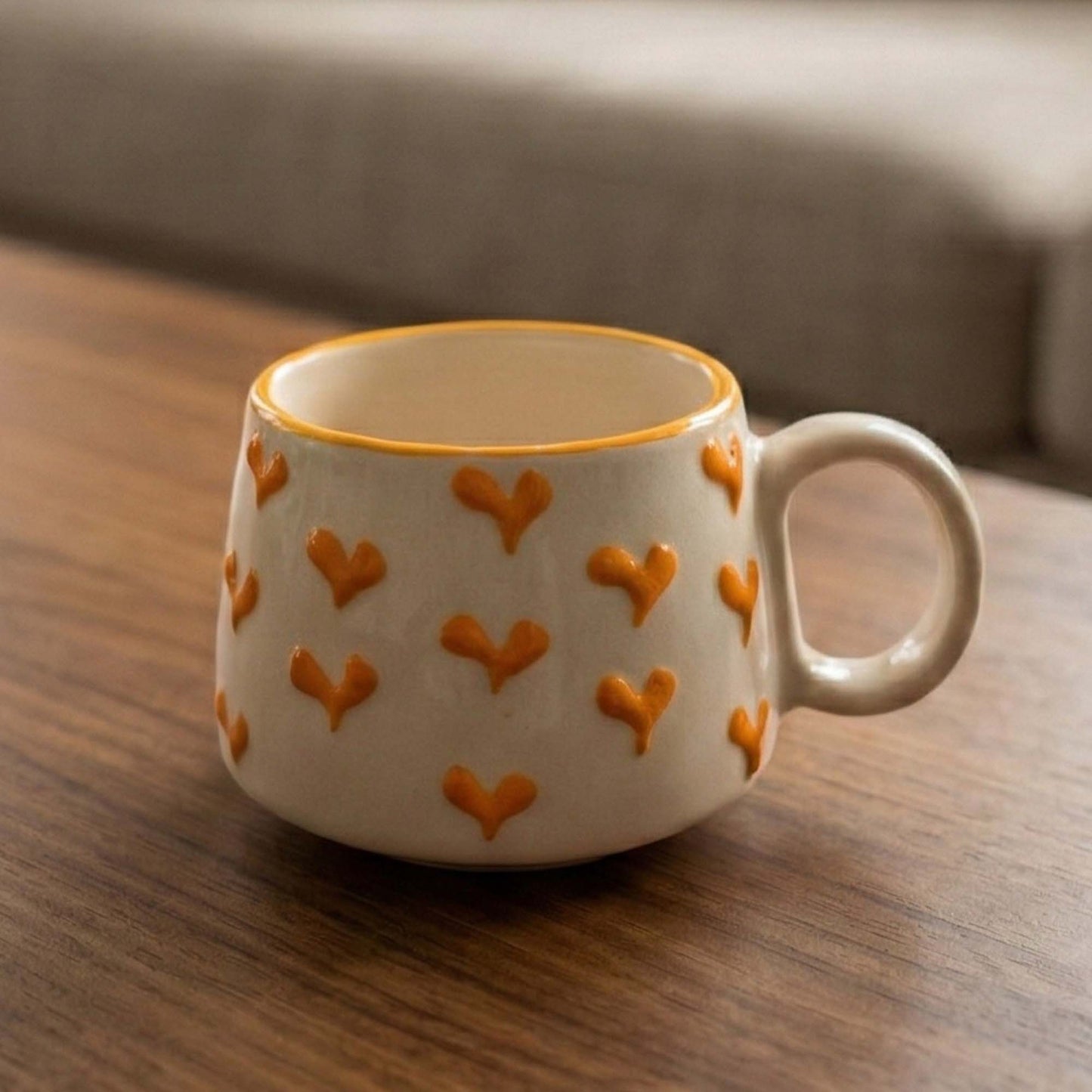 Ceramic mug with orange heart patterns on a wooden surface
